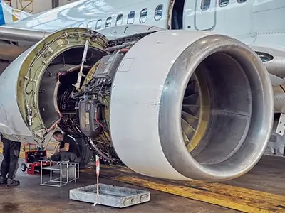 Aricraft engine with the hood up being working on in a hangar